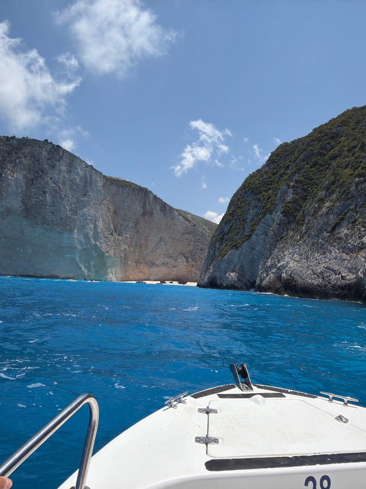 White boat cruises past dramatic cliffs on open ocean