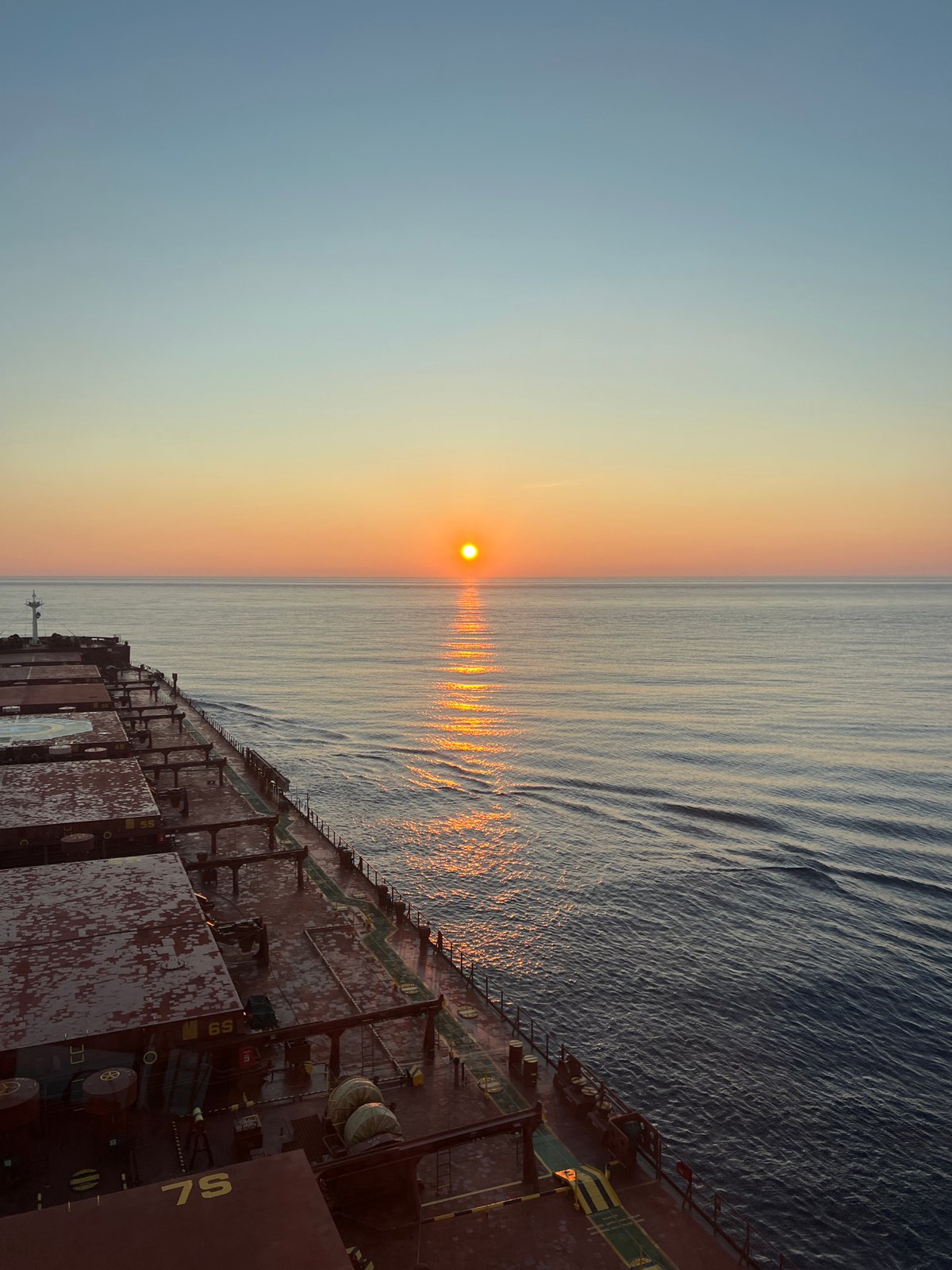 Cargo ship crosses open ocean at golden hour