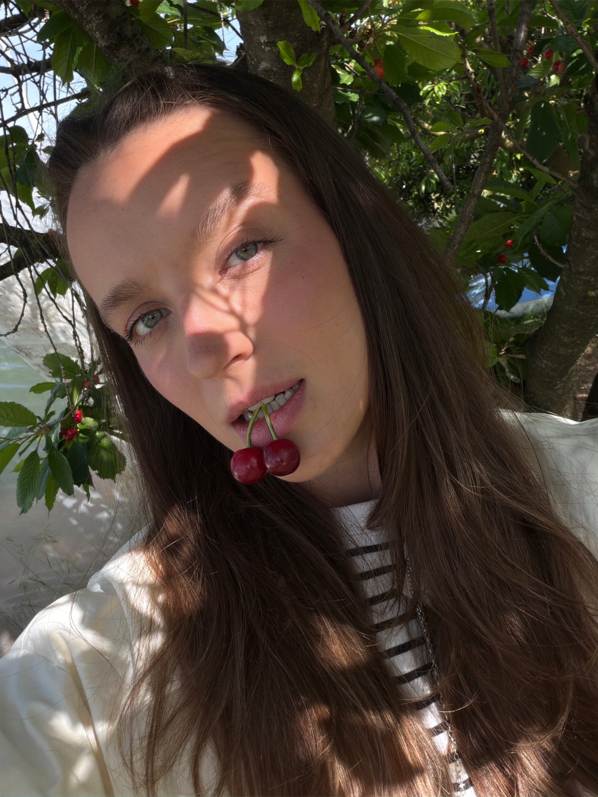 Woman photographed with cherries under fruit tree in Montenegro