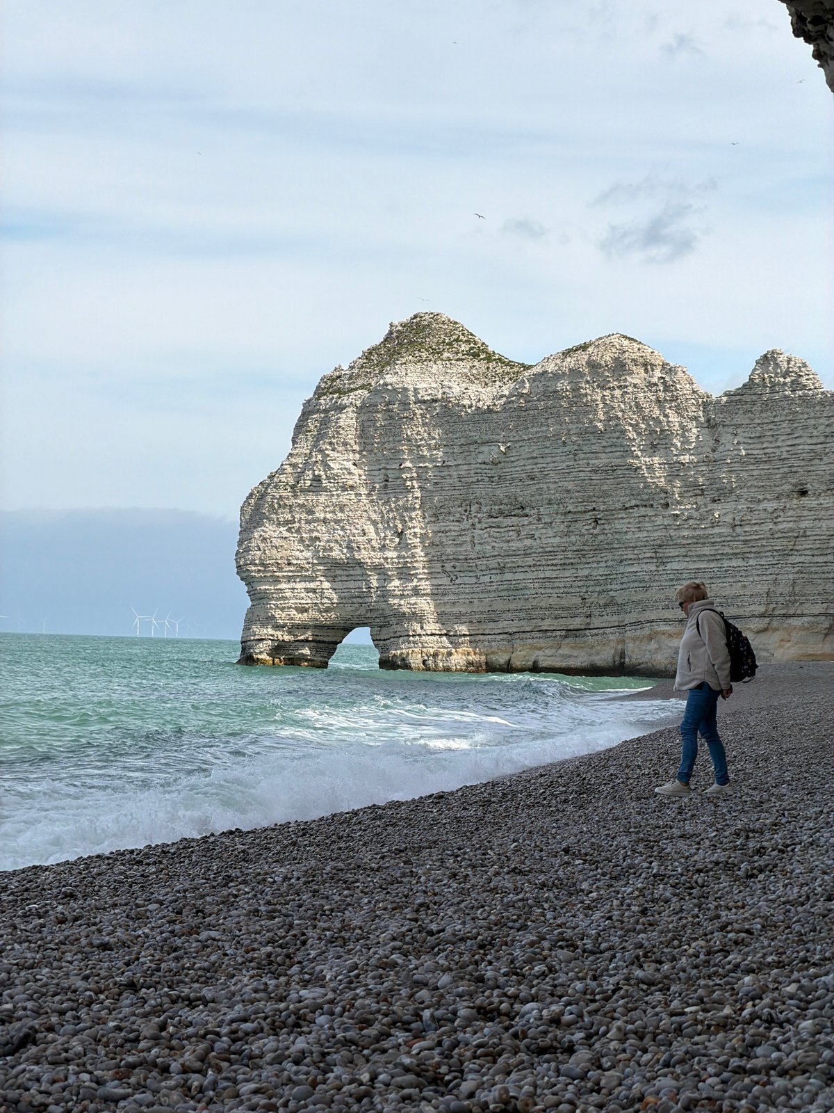 Woman relaxes on rocky beach near Étretat's famous cliffs