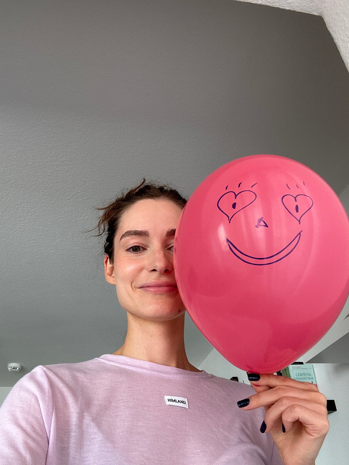 Woman poses with pink balloon against wall in Kiel