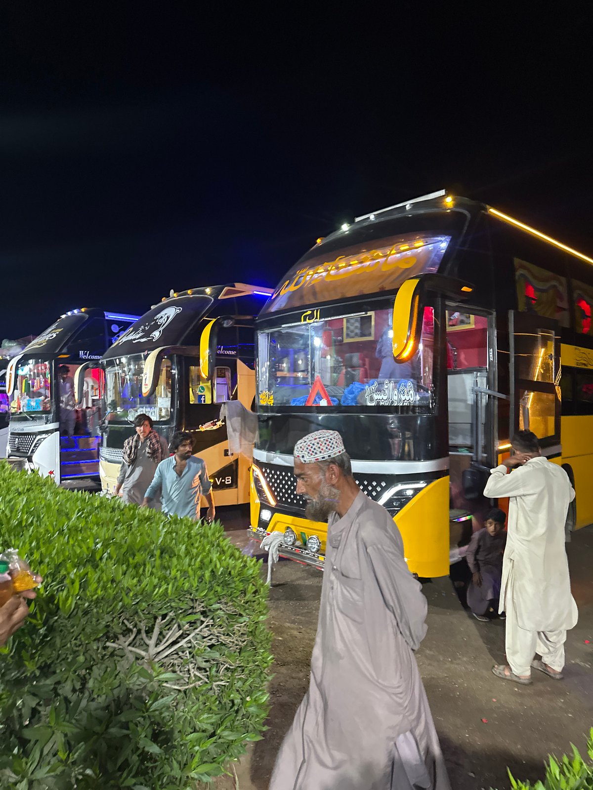 Decorated buses and snack stalls observed at nighttime terminal