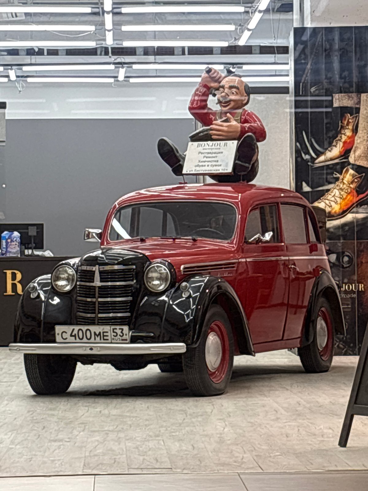 Vintage car art display features whimsical shoemaker figurine