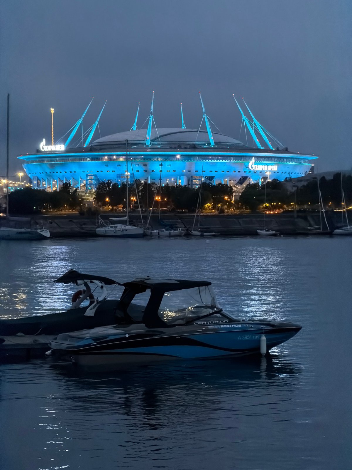 Gazprom Arena glows blue over Saint Petersburg's sailboat-filled marina