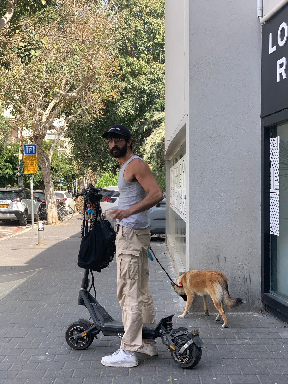 Man with dog and scooter spotted on Tel Aviv sidewalk