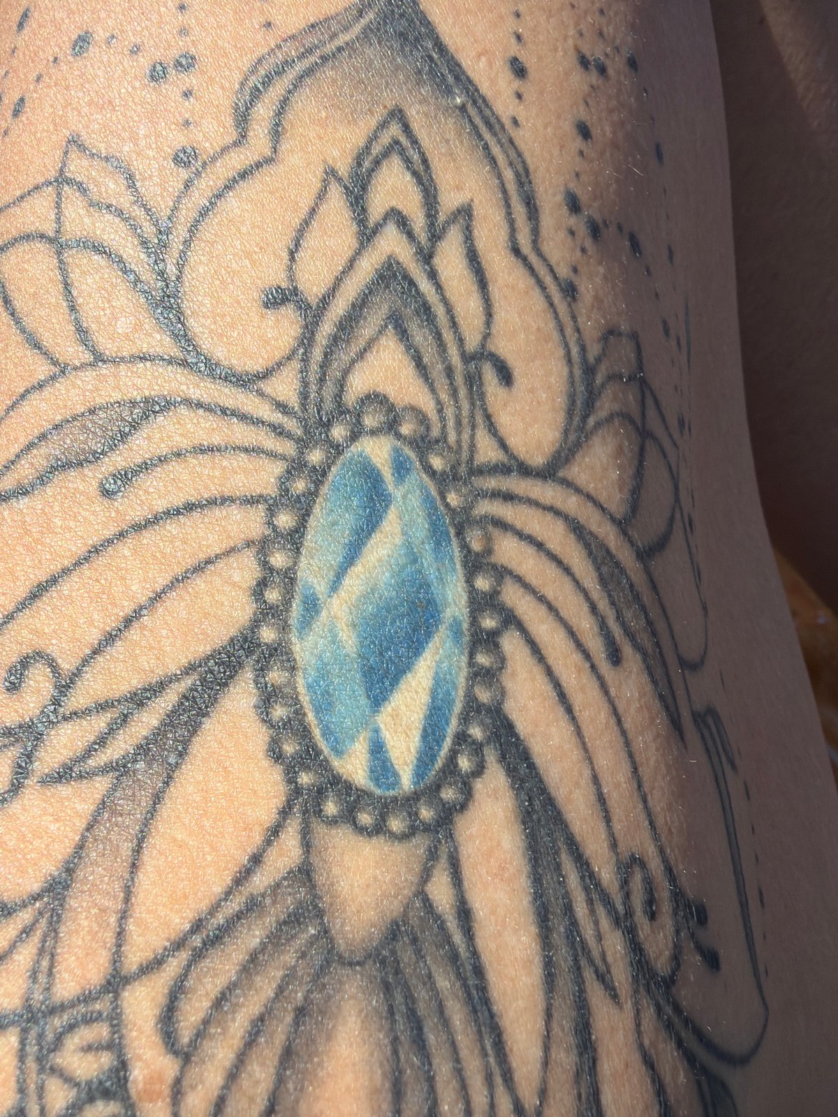 Floral tattoo with blue geometric pattern documented in Al Hadaba