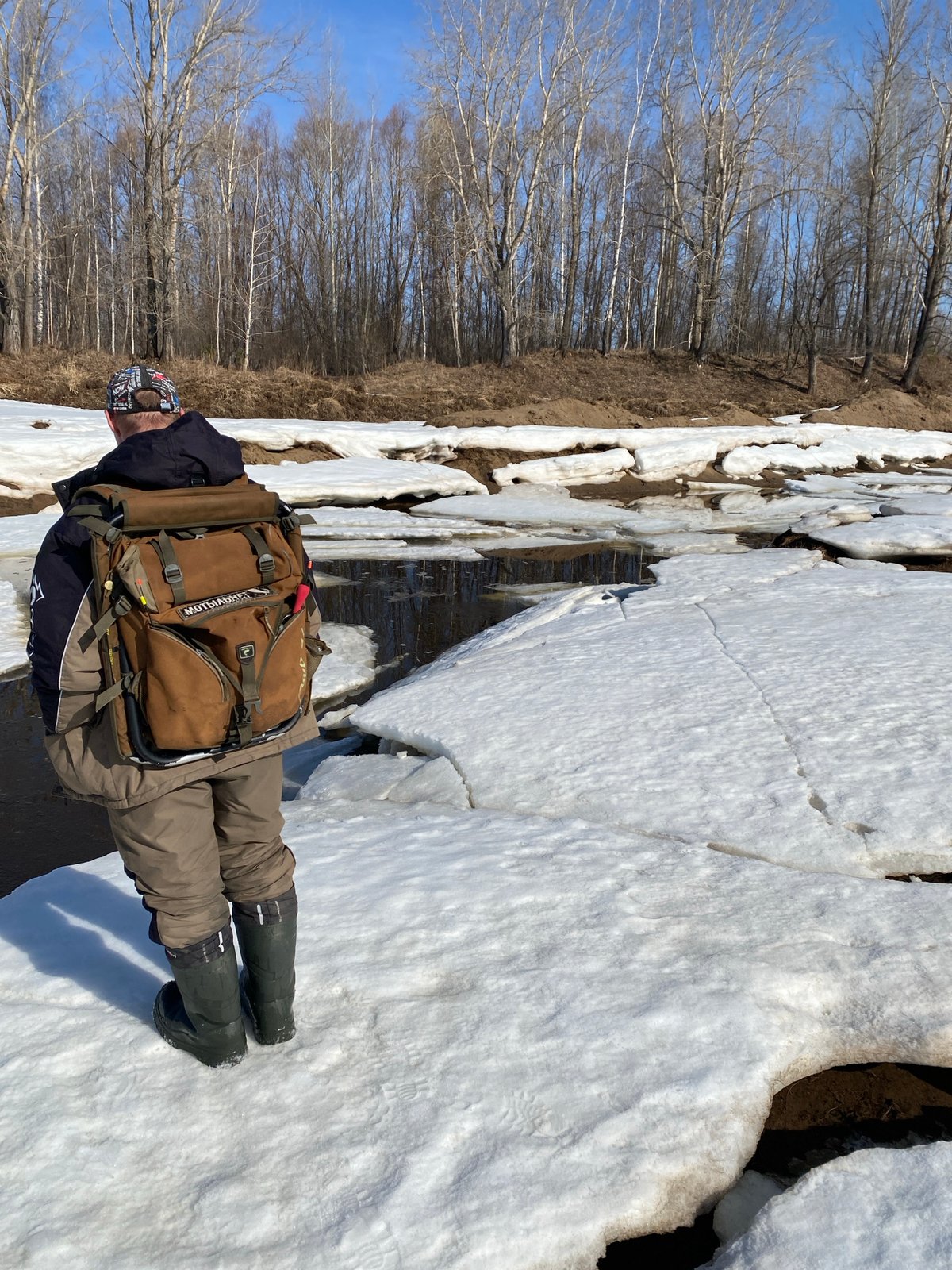 Winter hiker crosses cracked ice in rural Russia
