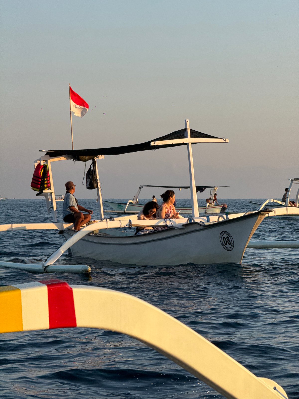 Traditional outrigger boats cross Bali's waters at sunset