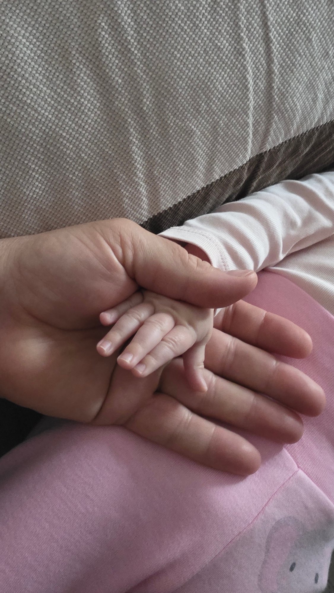 Adult tenderly holds baby in early morning moment, Bulgaria