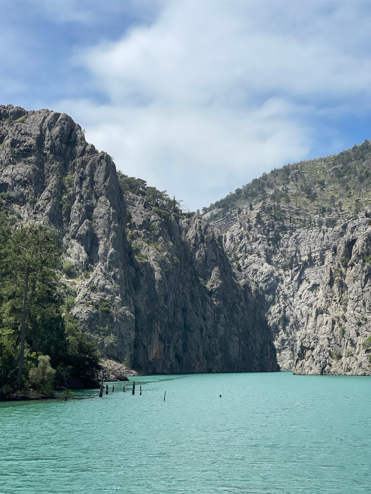 Boat crosses turquoise mountain lake under cloudy skies