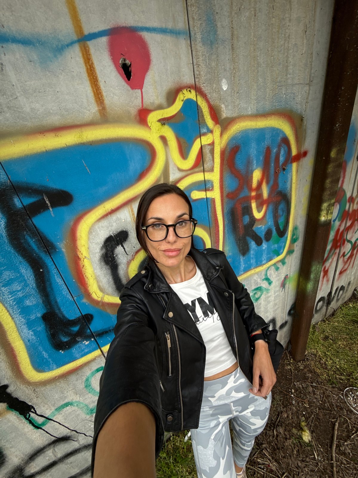 Woman poses for casual portrait on graffitied concrete in Pleven