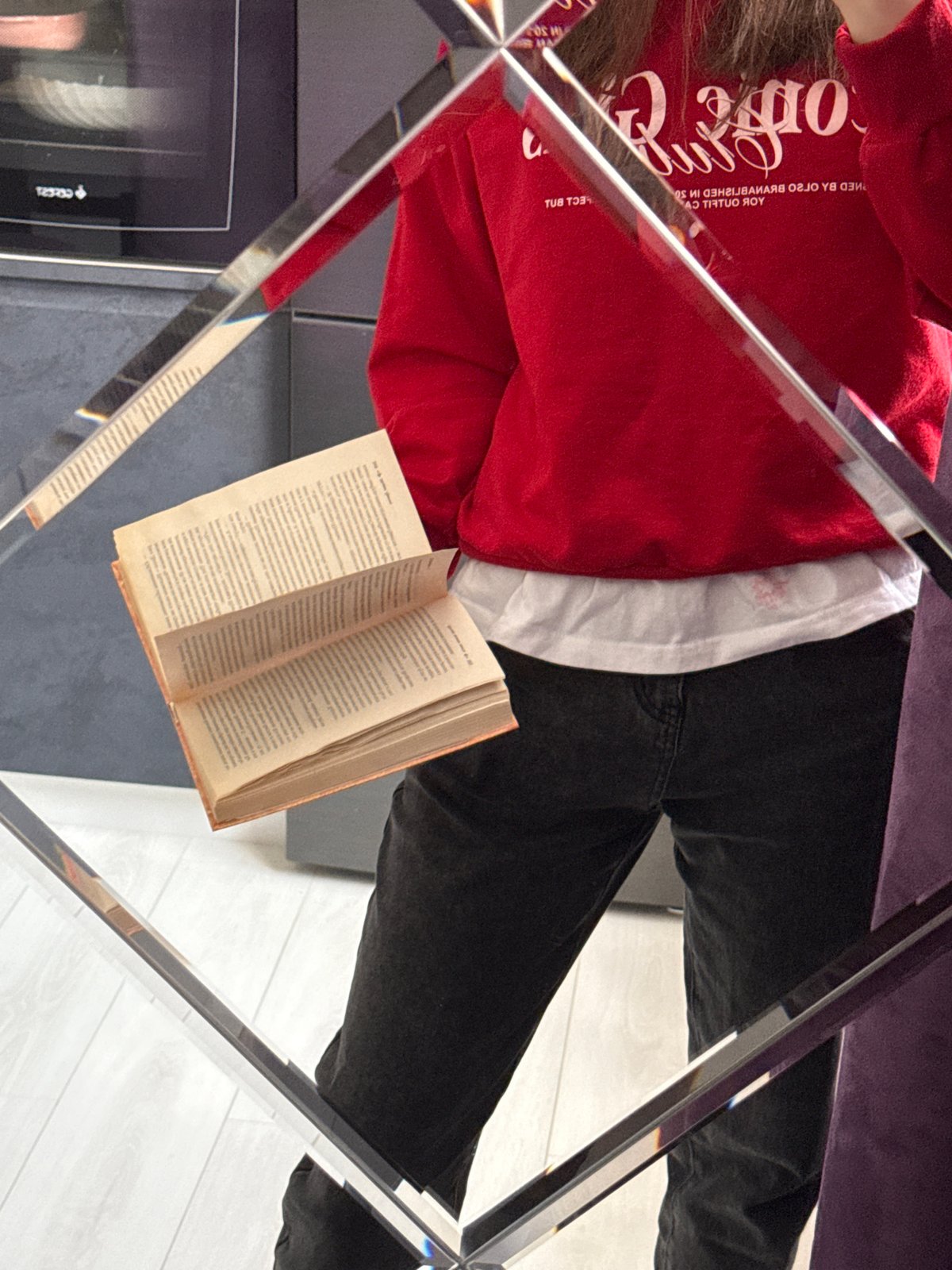 Person reading Cyrillic book captured through mirrors in home