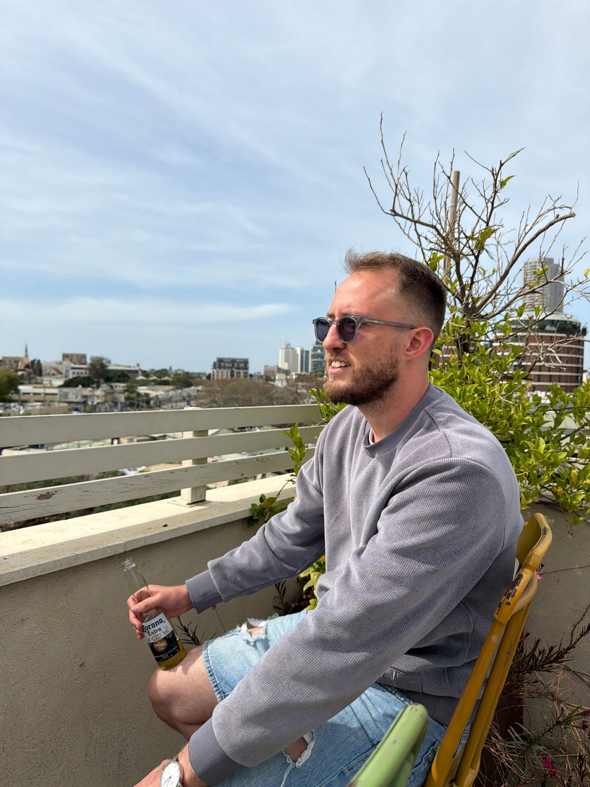 Man smiles on Tel Aviv rooftop during sunny afternoon