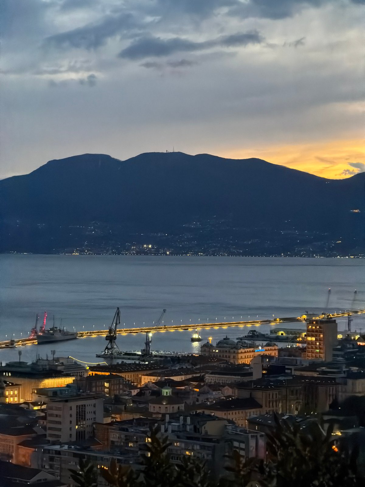 Aerial dusk view captures illuminated Rijeka cityscape and waterfront