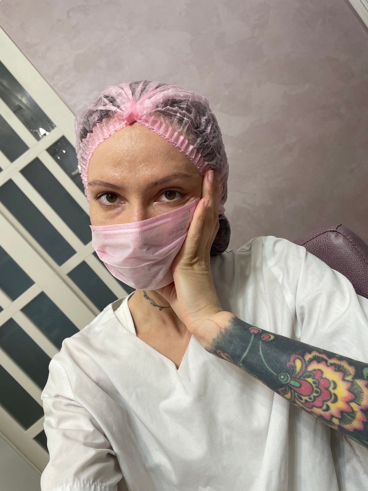 Woman in pink medical gear observed indoors in Izhevsk