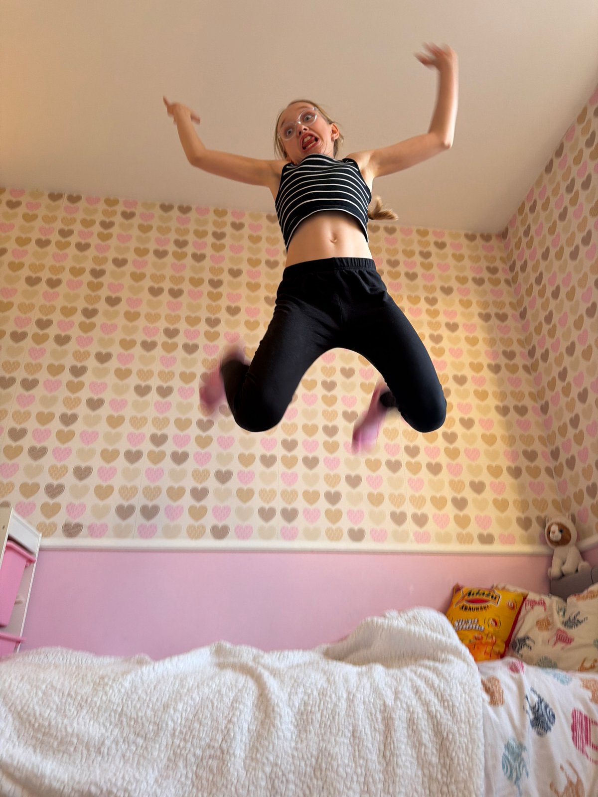 Young person photographed in playful bedroom poses in Latvia