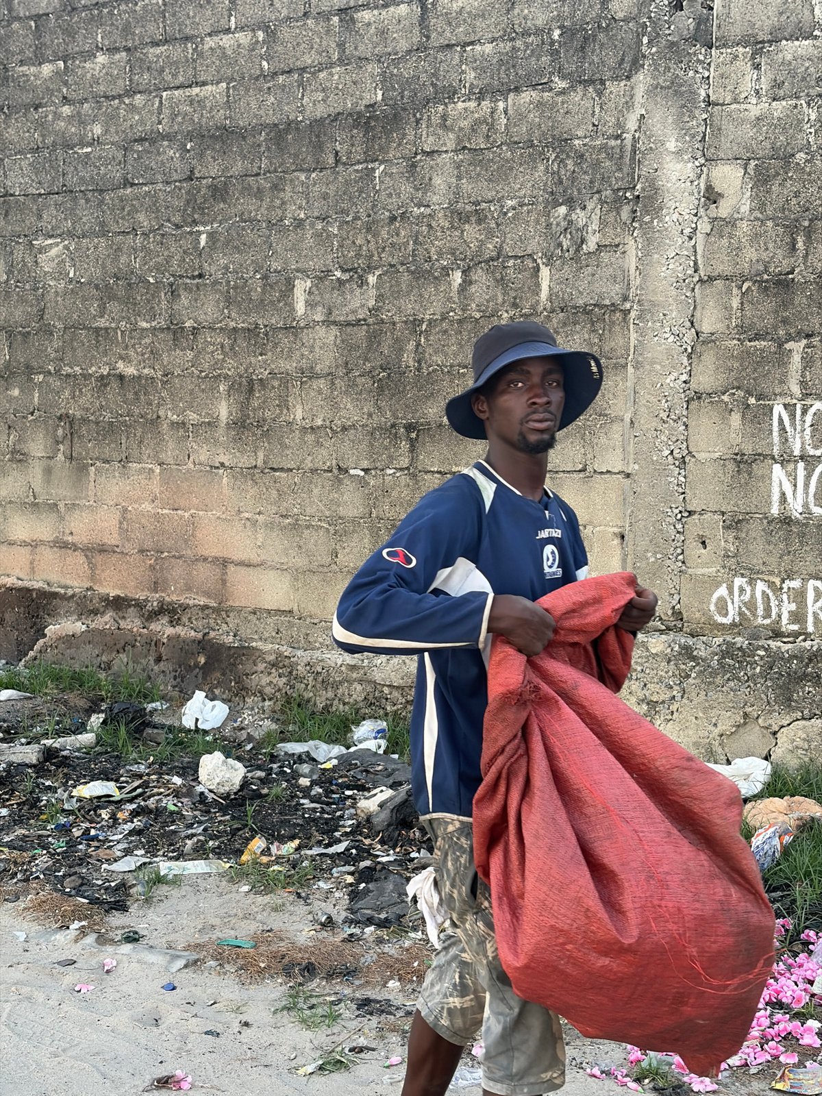 Man with red bag observed near graffitied wall in Alaguntan