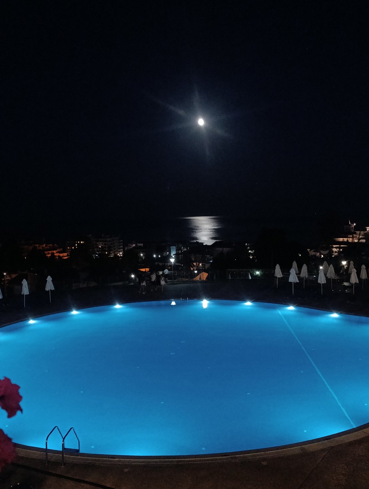 Full moon casts shimmering path over city-lit coastal waters