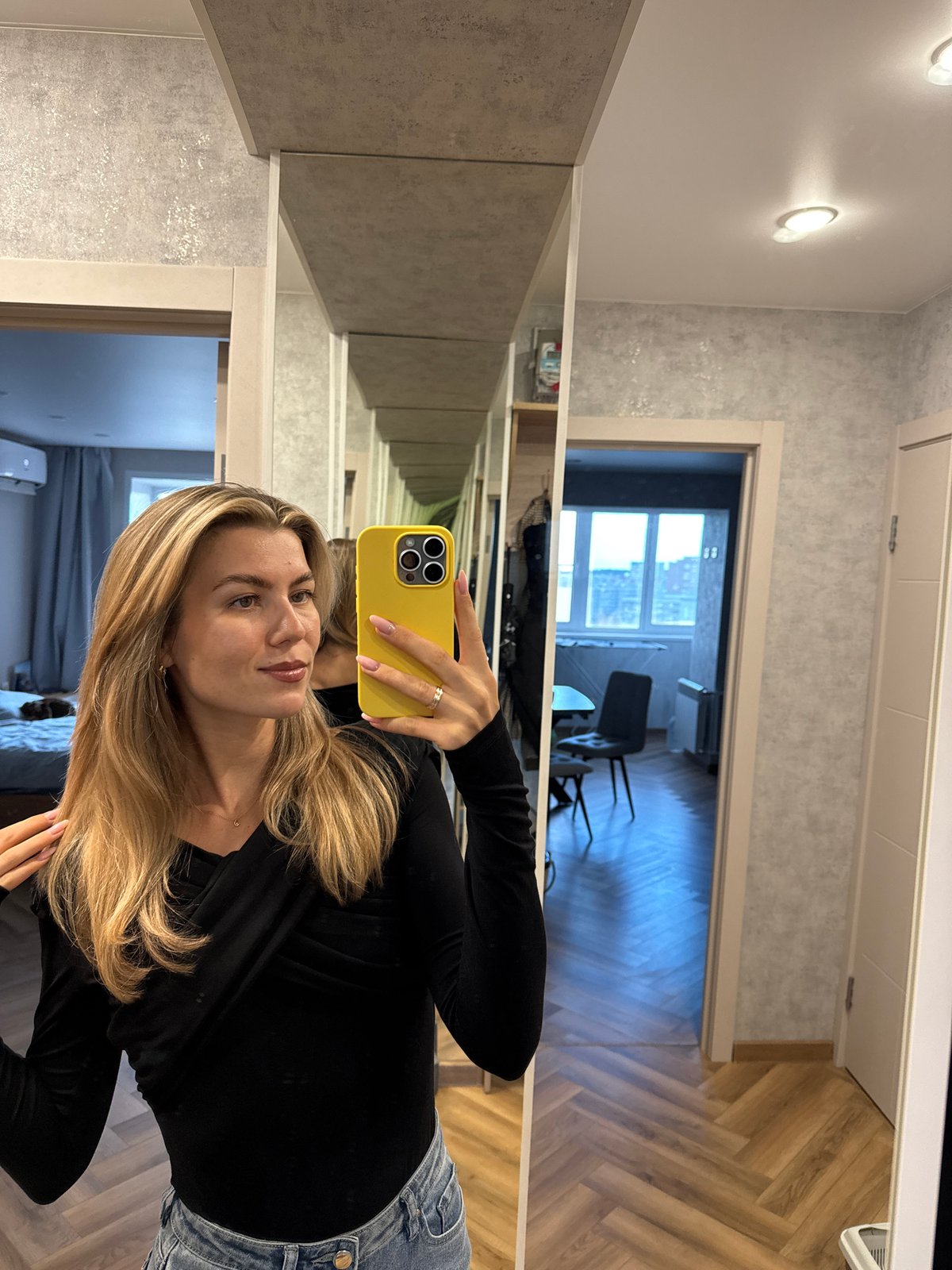 Woman takes selfies, Bengal cat rests indoors amid city views