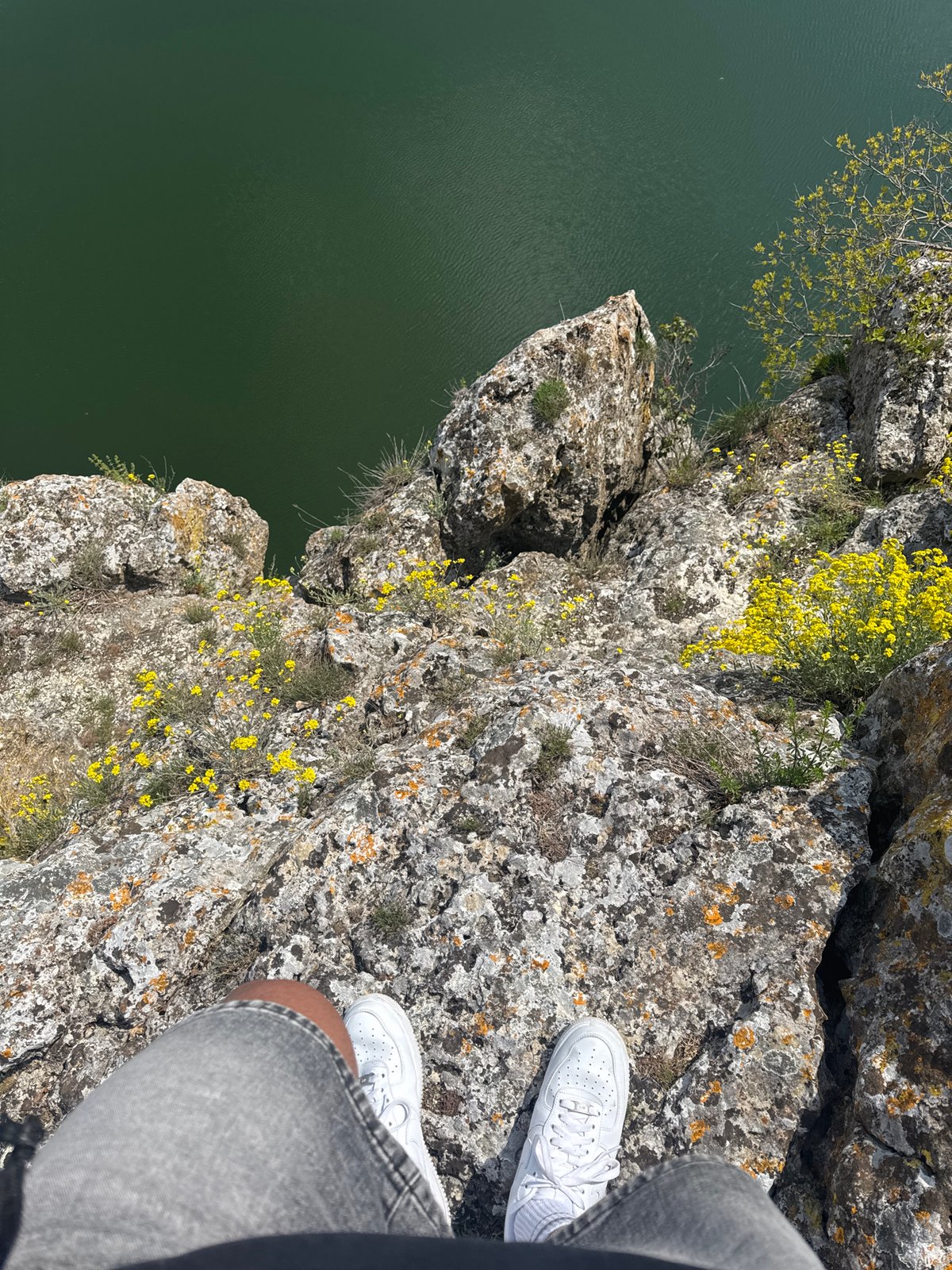 Photographer captures cliff-edge view overlooking water from precarious position