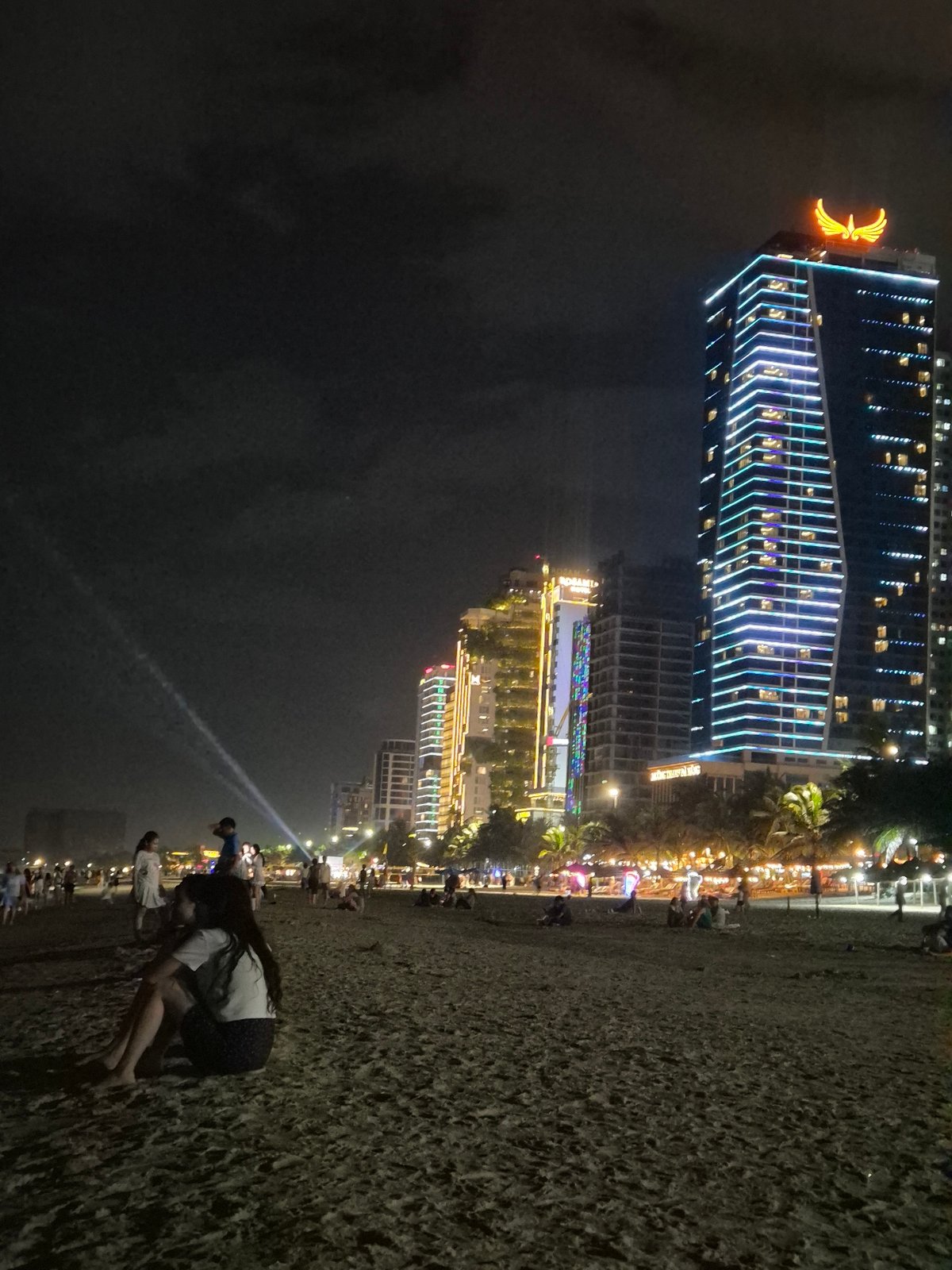 Night out on Đà Nẵng beach with the city glowing behind