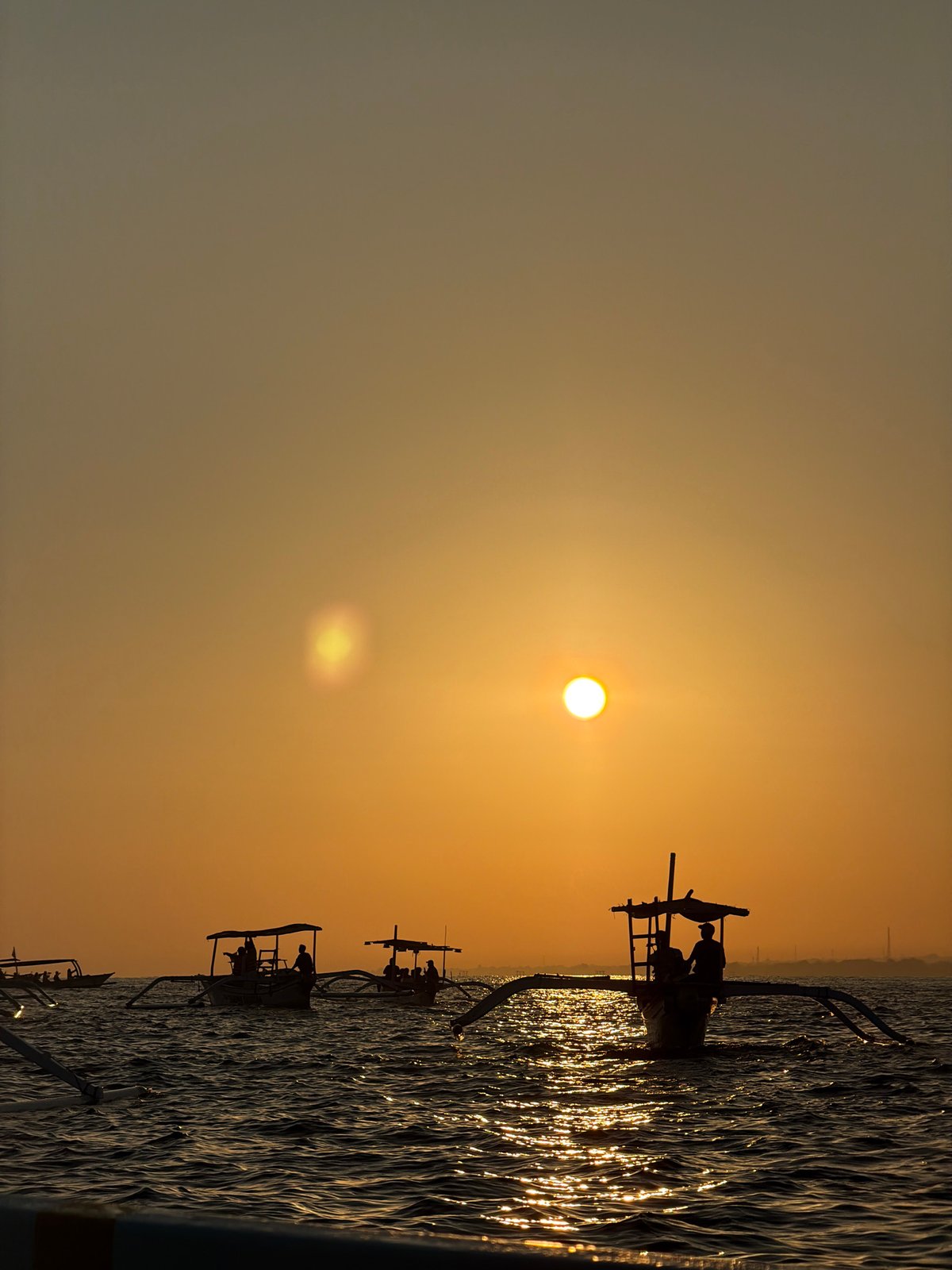 Outrigger boats silhouetted at sunset off Buleleng, Bali