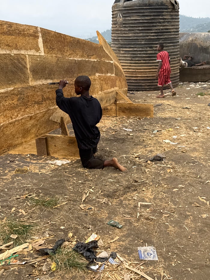 Young man kneels outdoors in Limbé III, Cameroon