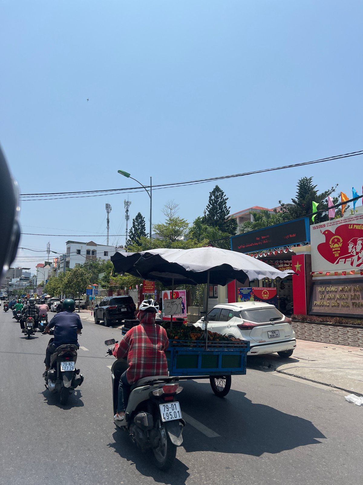 Motorcyclist travels busy Nha Trang street under clear skies