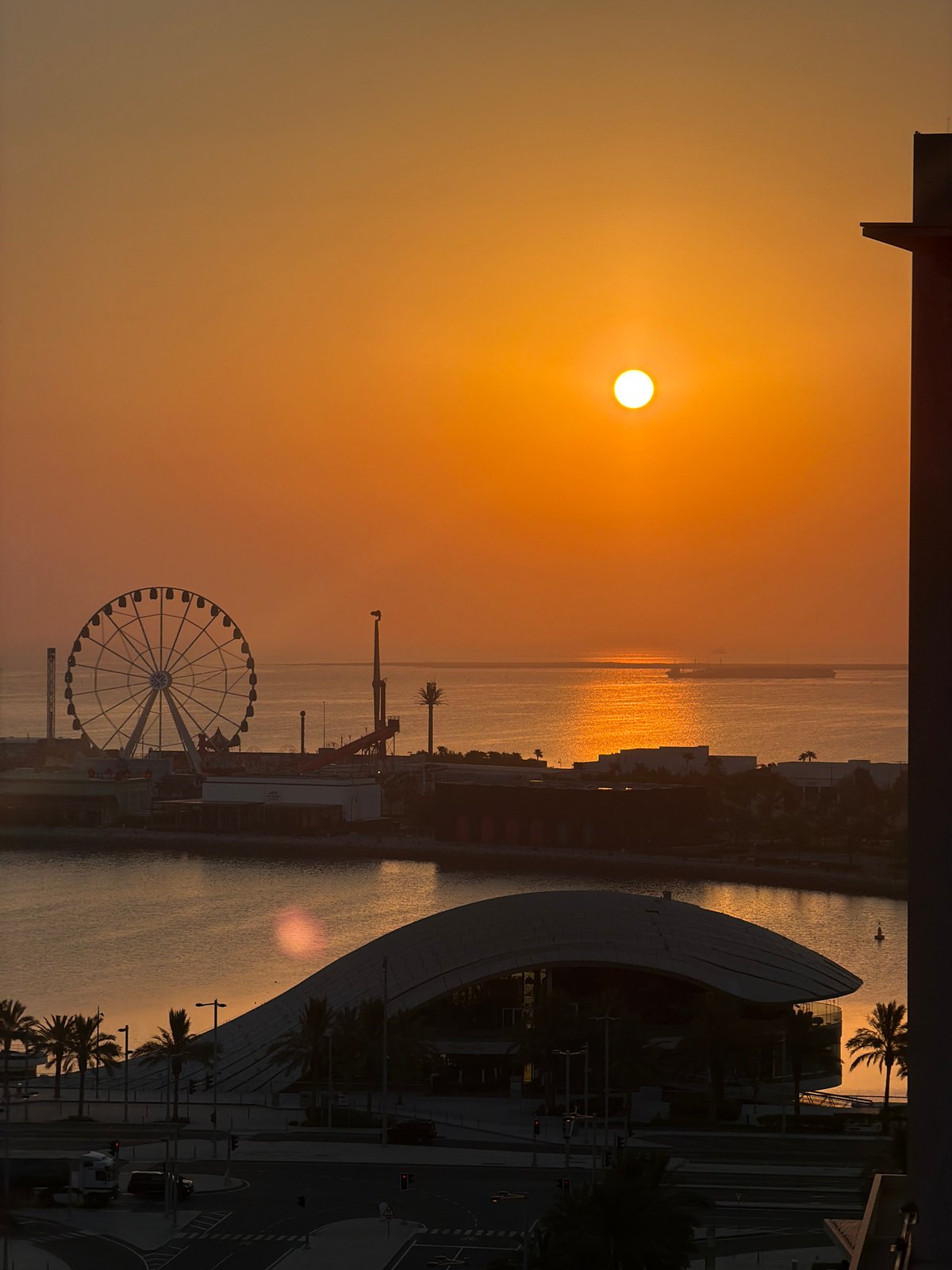 Sunset over a city waterfront with a Ferris wheel