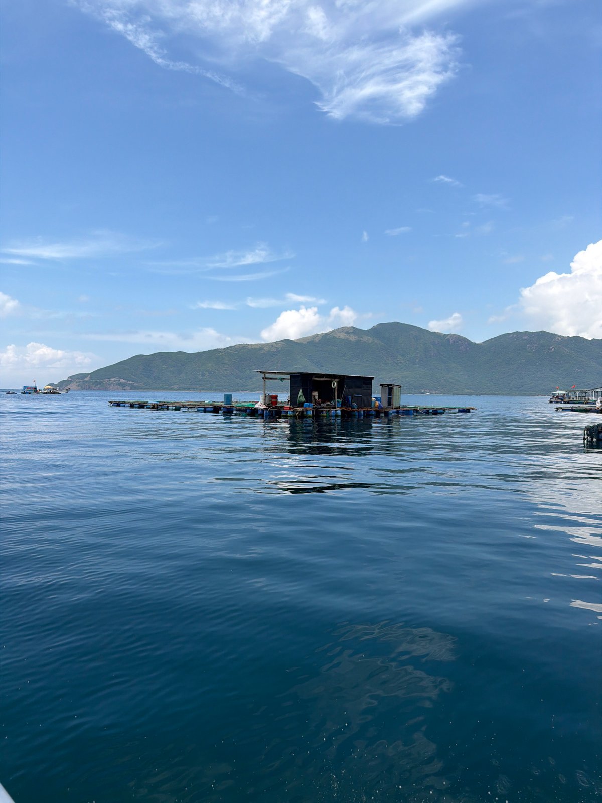 Boat approaches floating village near Vietnamese aquaculture farms