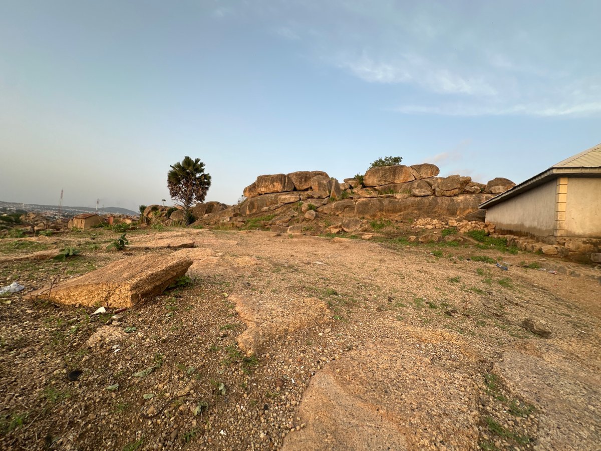 Two people overlook Jos settlement from rocky hilltop at sunset