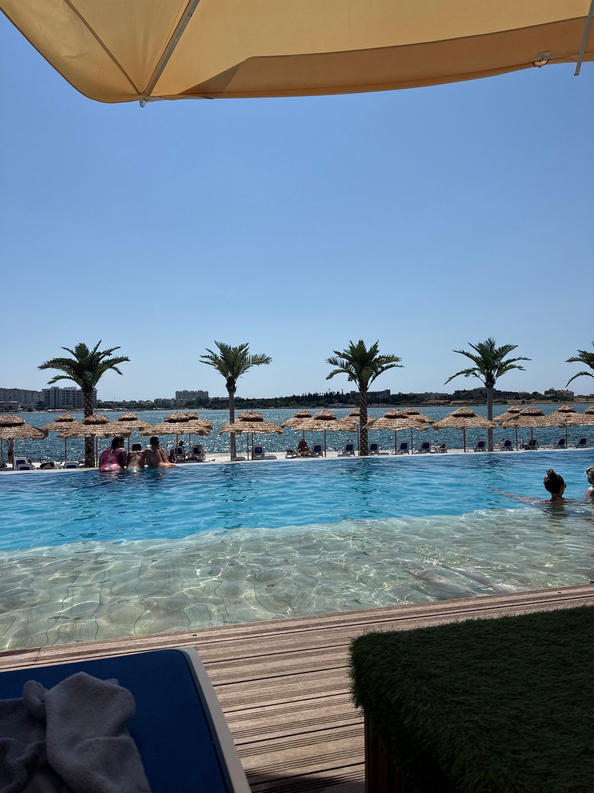 Infinity pool and beach lounges at a sunny coastal resort