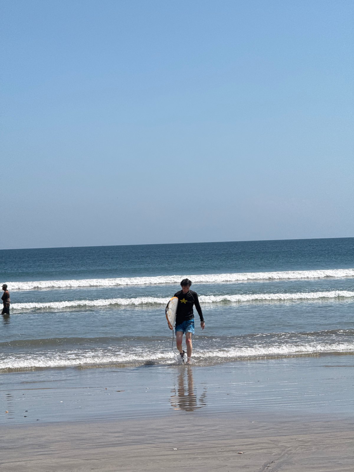 Surfers in and out of the water at Kuta Beach, Bali