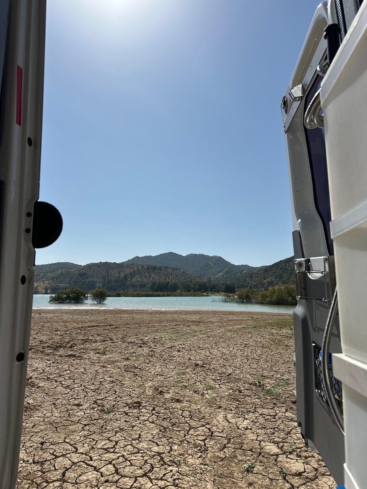 Camper van parked by a dry Andalusian reservoir, midsummer.