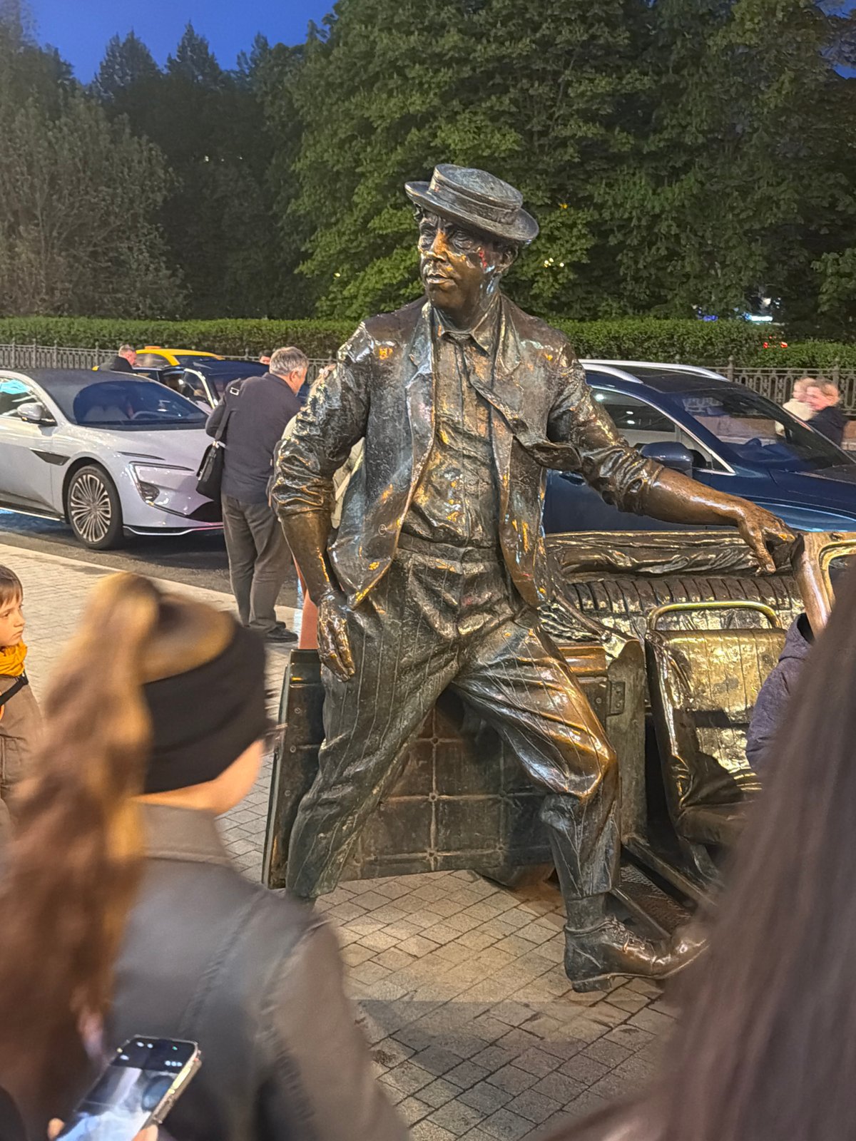 Evening street scenes recorded near bronze statue in Moscow