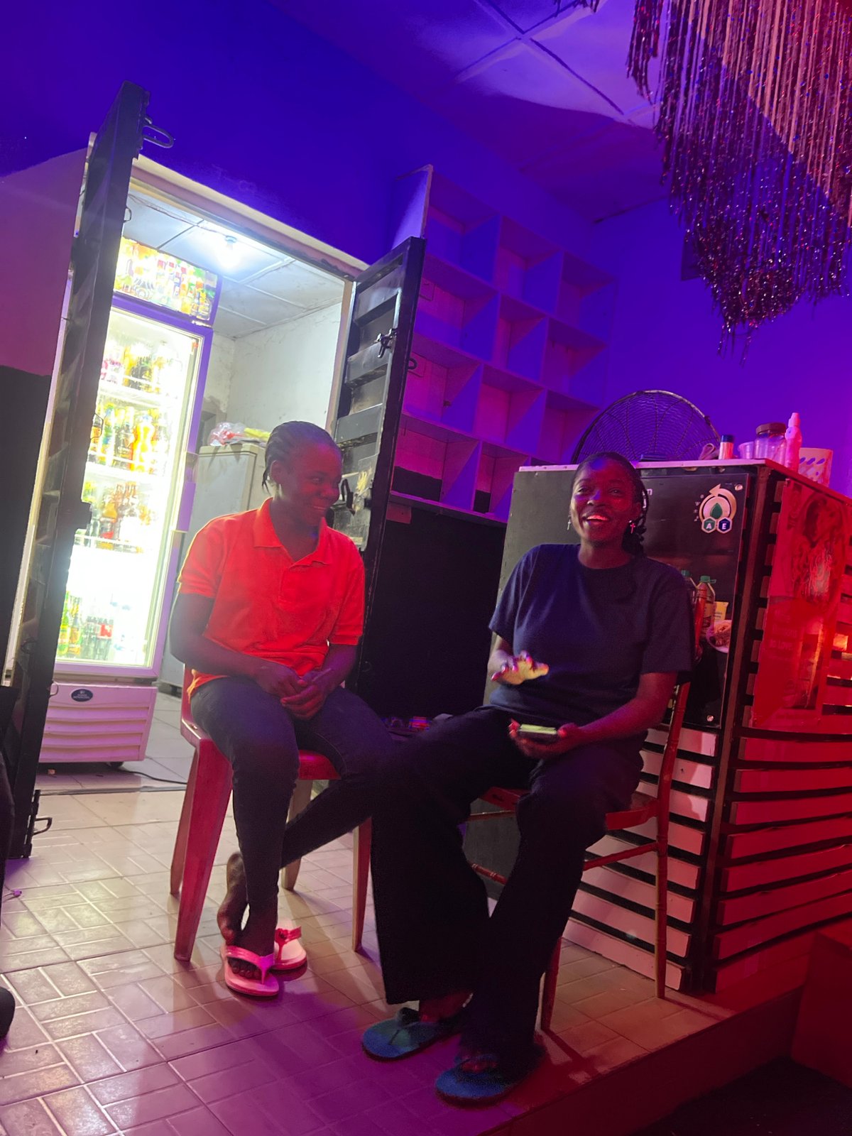 Two people converse at indoor venue in Howayi, Nigeria
