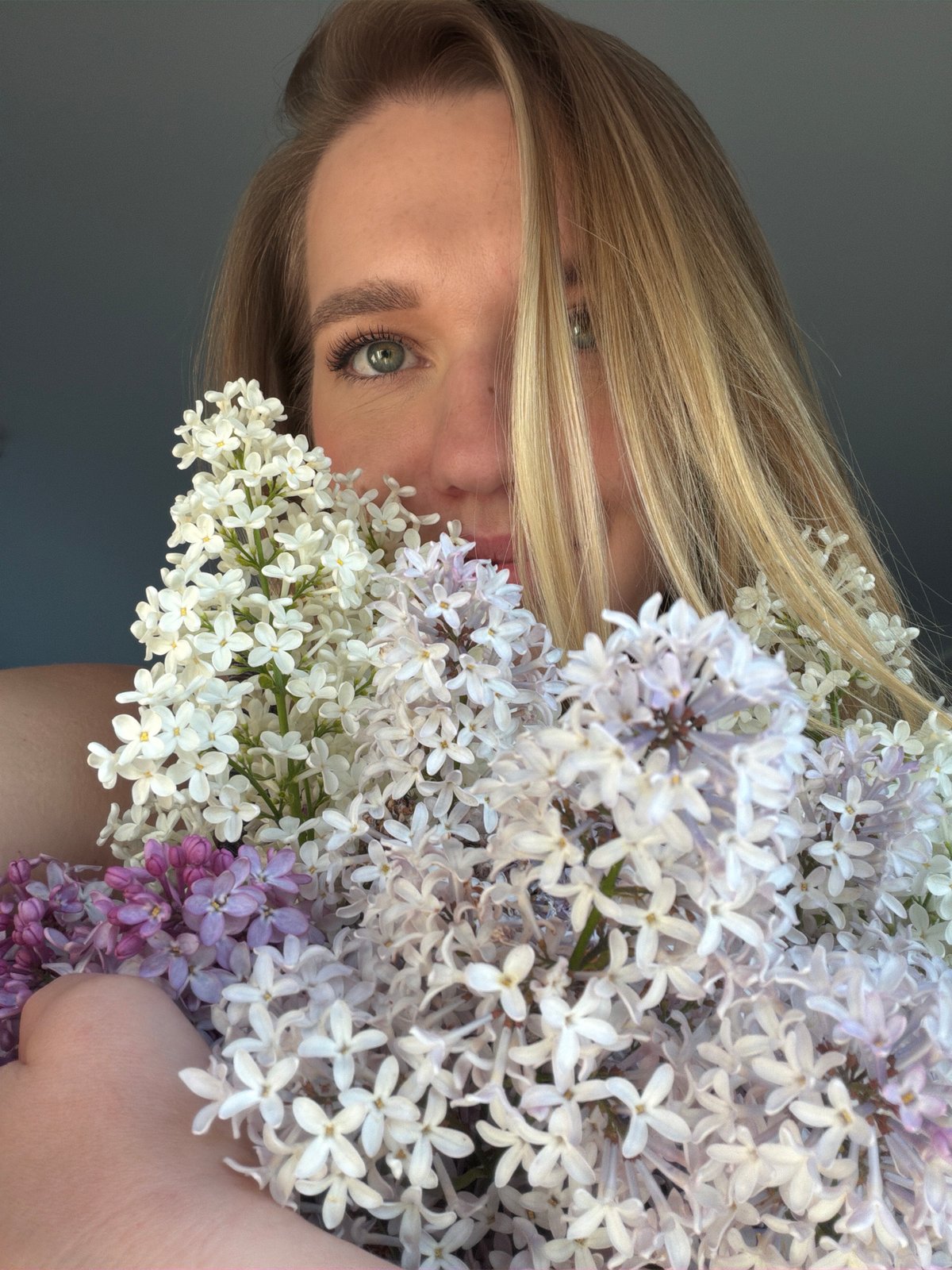 Woman arranges spring lilacs at home with black cat