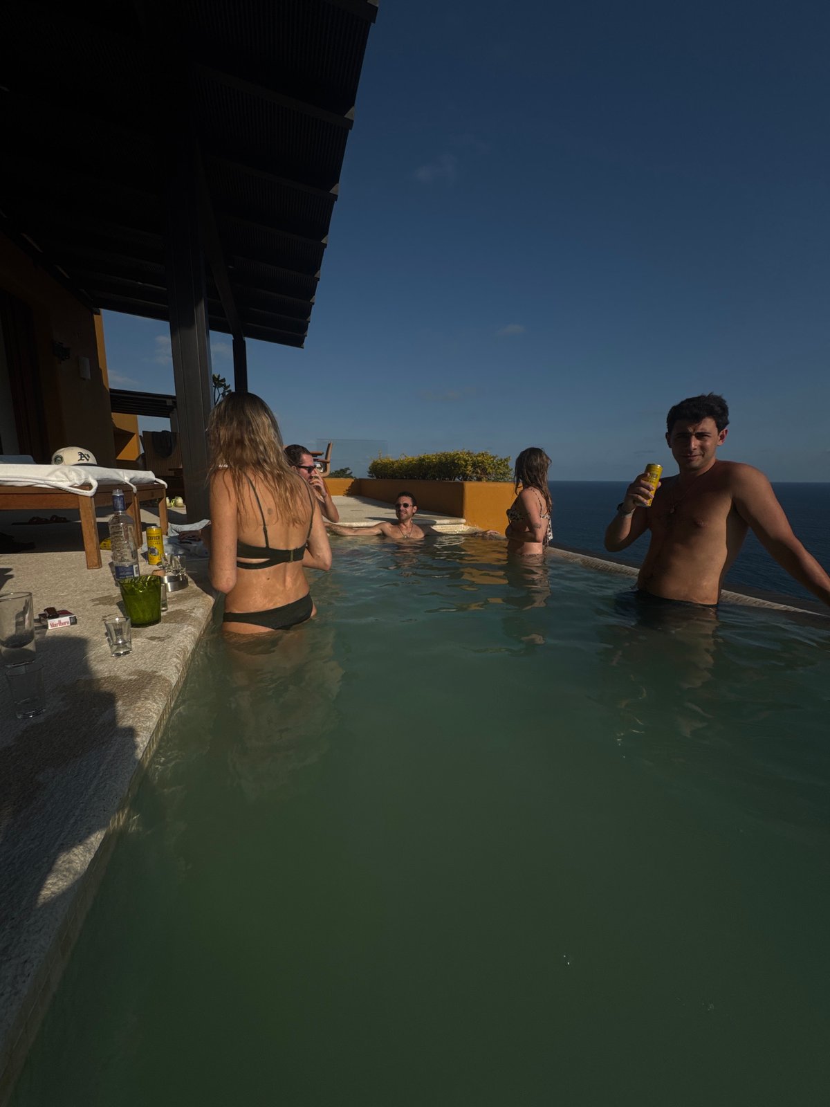 People enjoy infinity pool on sunny day in Puerto Marqués
