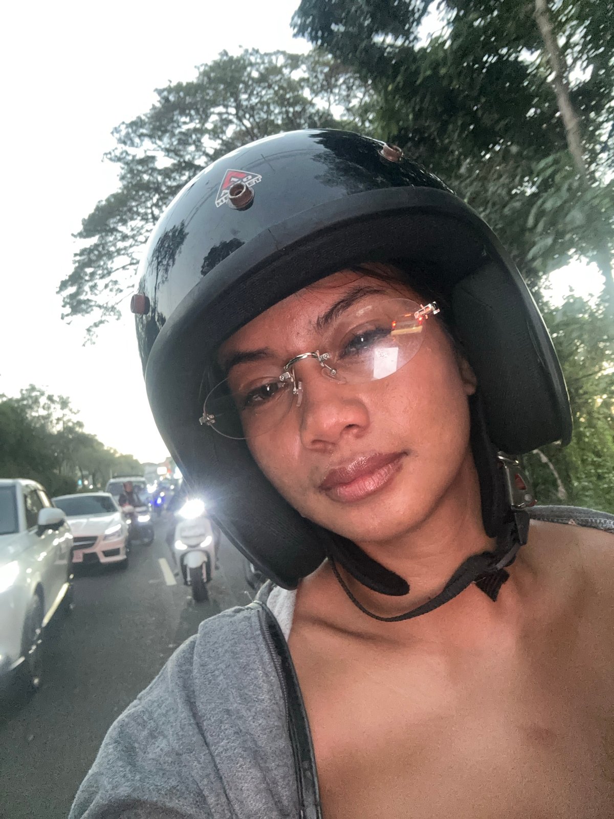 Helmeted scooter riders pause for a selfie in Denpasar traffic