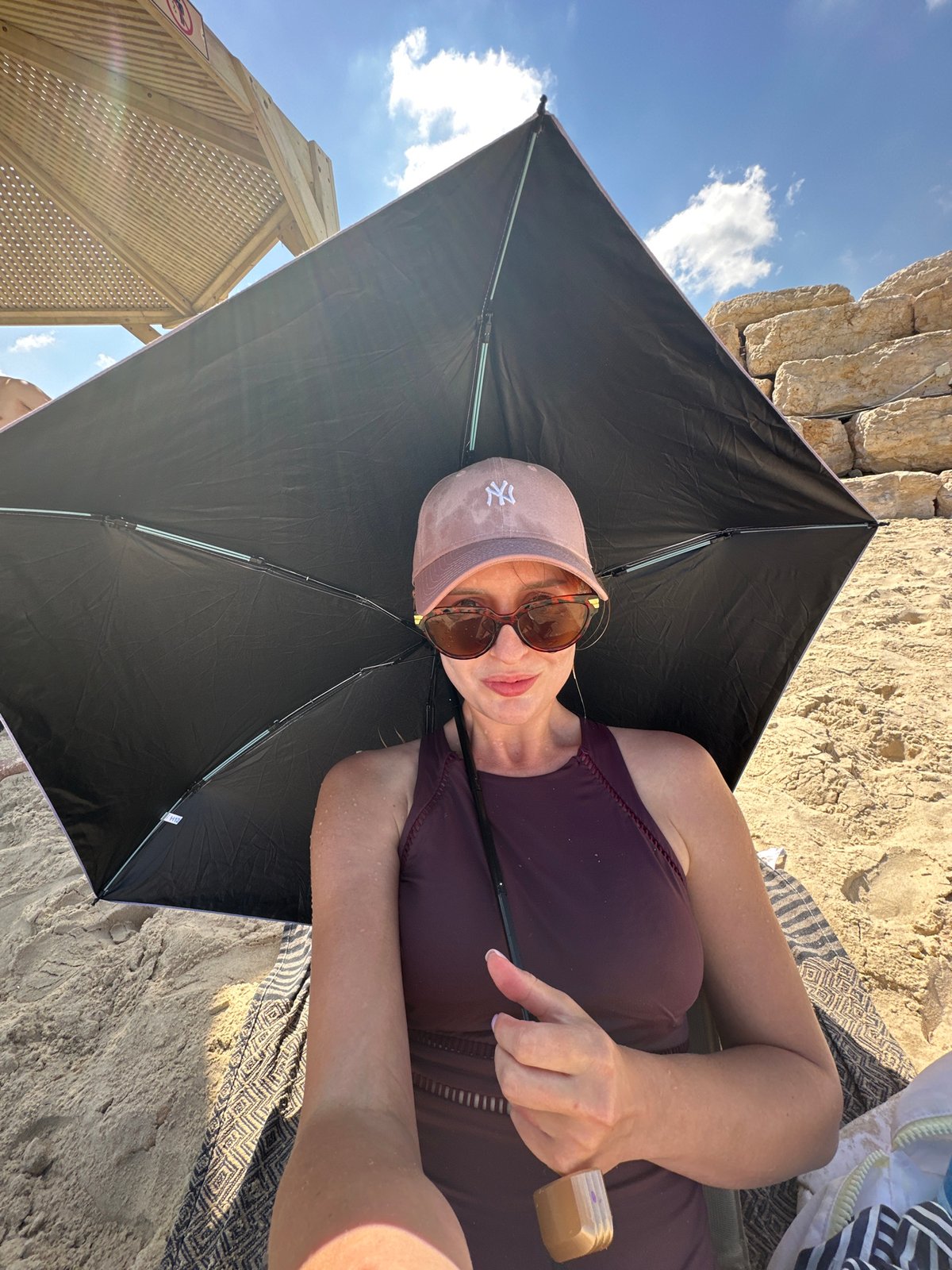 Relaxing under a black umbrella on a sunny Tel Aviv beach