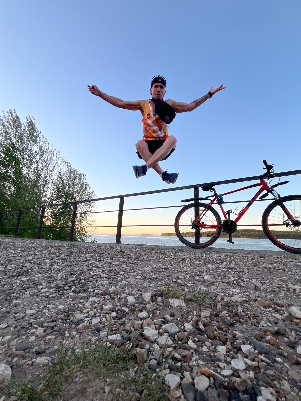 Cyclist performs stretches along Kama River waterfront in Chaikovsky
