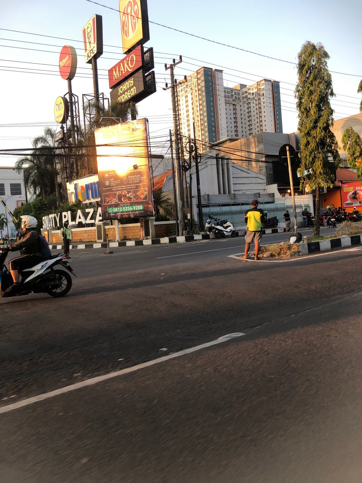 Sidoarjo street traffic at golden hour, riders and vendors