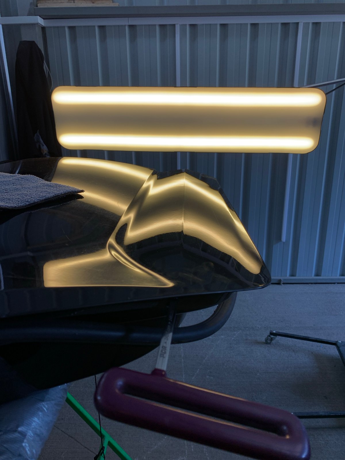 Dent repair in progress on a reflective black car hood