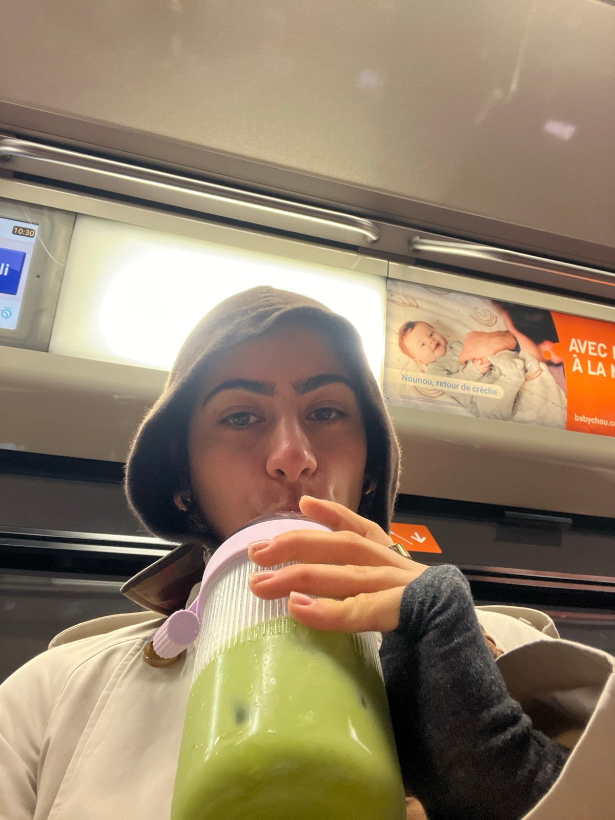 Woman drinks green beverage on public transport during morning commute