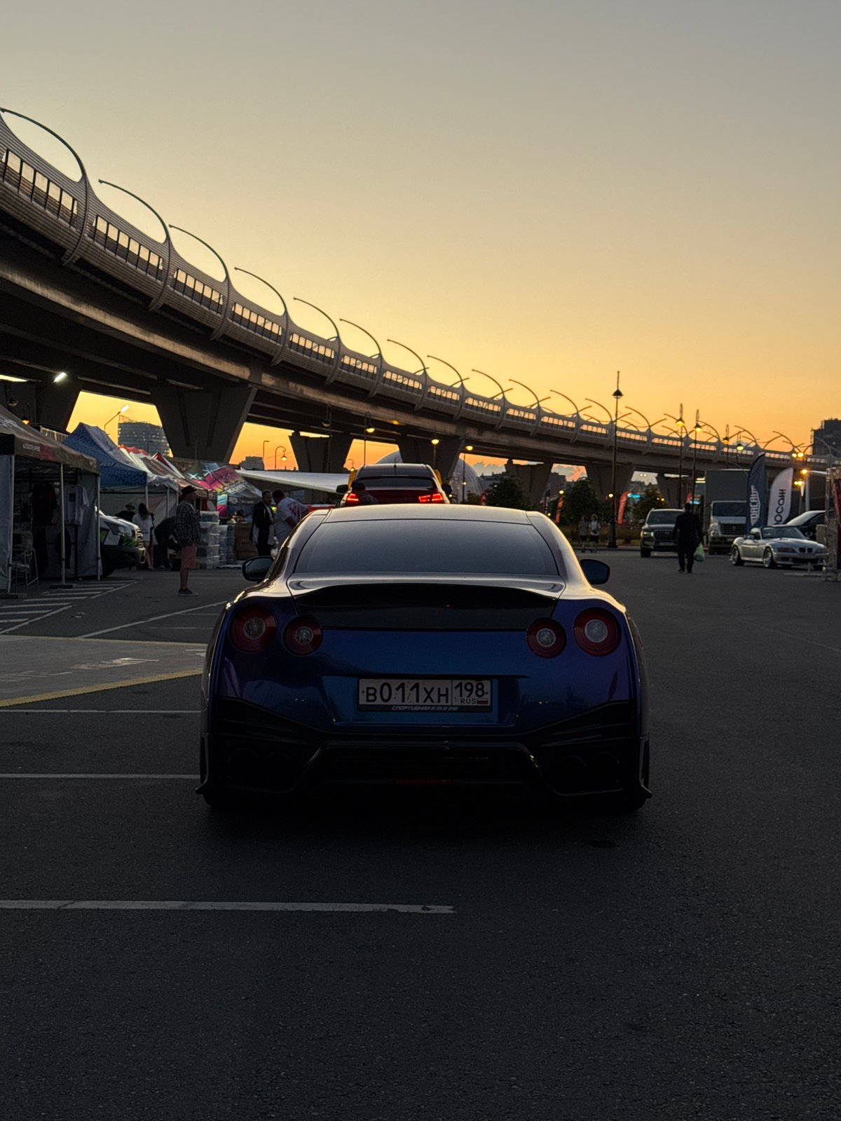Performance cars and a tow truck near a St. Petersburg overpass