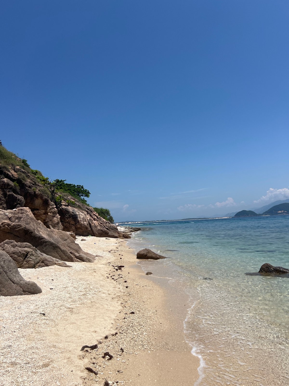 Early morning at Dai Lanh beach: clear water, rocky shore, mountain backdrop