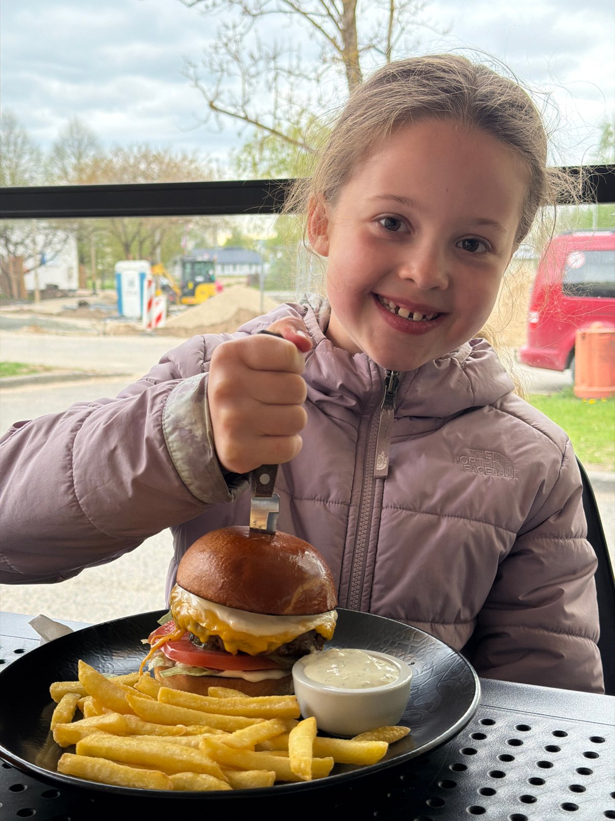 Girl enjoys hamburger lunch in Salaspils restaurant