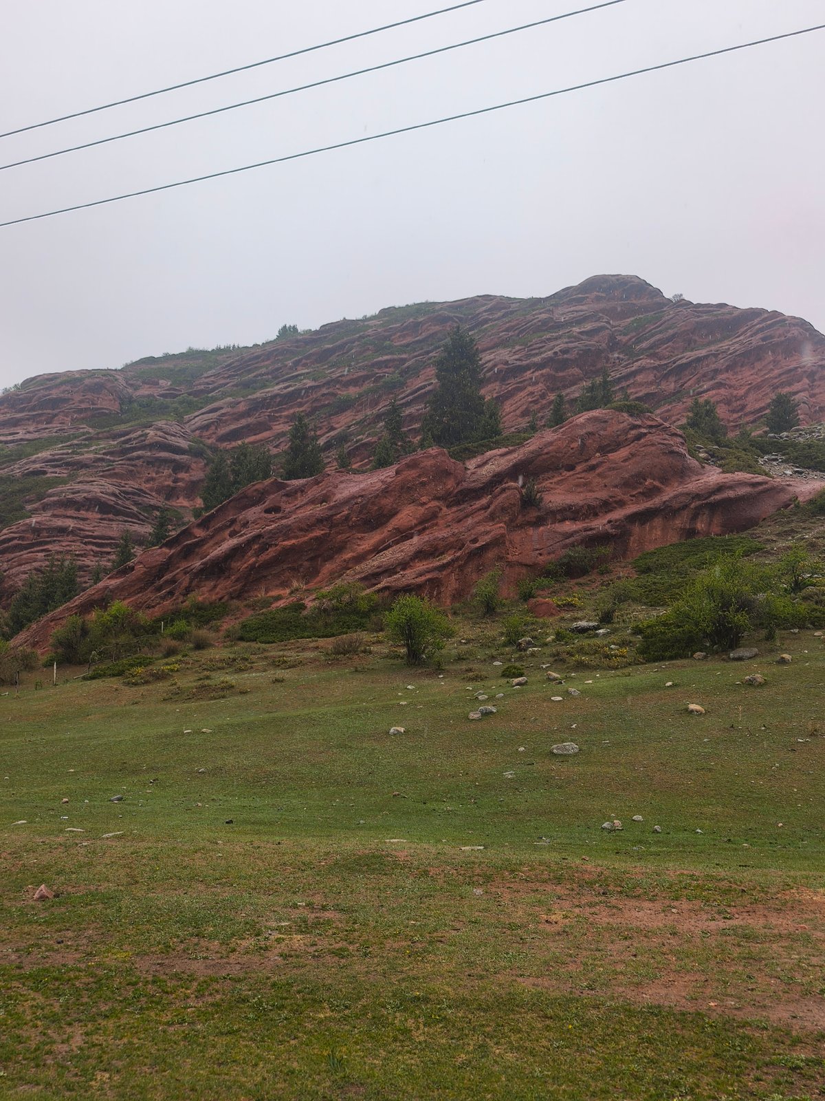 Red rock formations observed under overcast skies in Kyrgyzstan