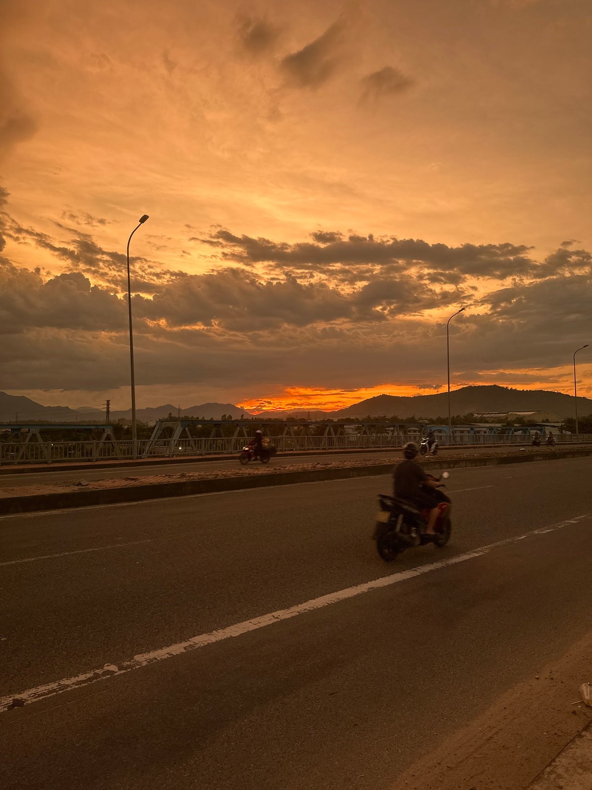 Bridge traffic flows through a fiery Da Nang sunset