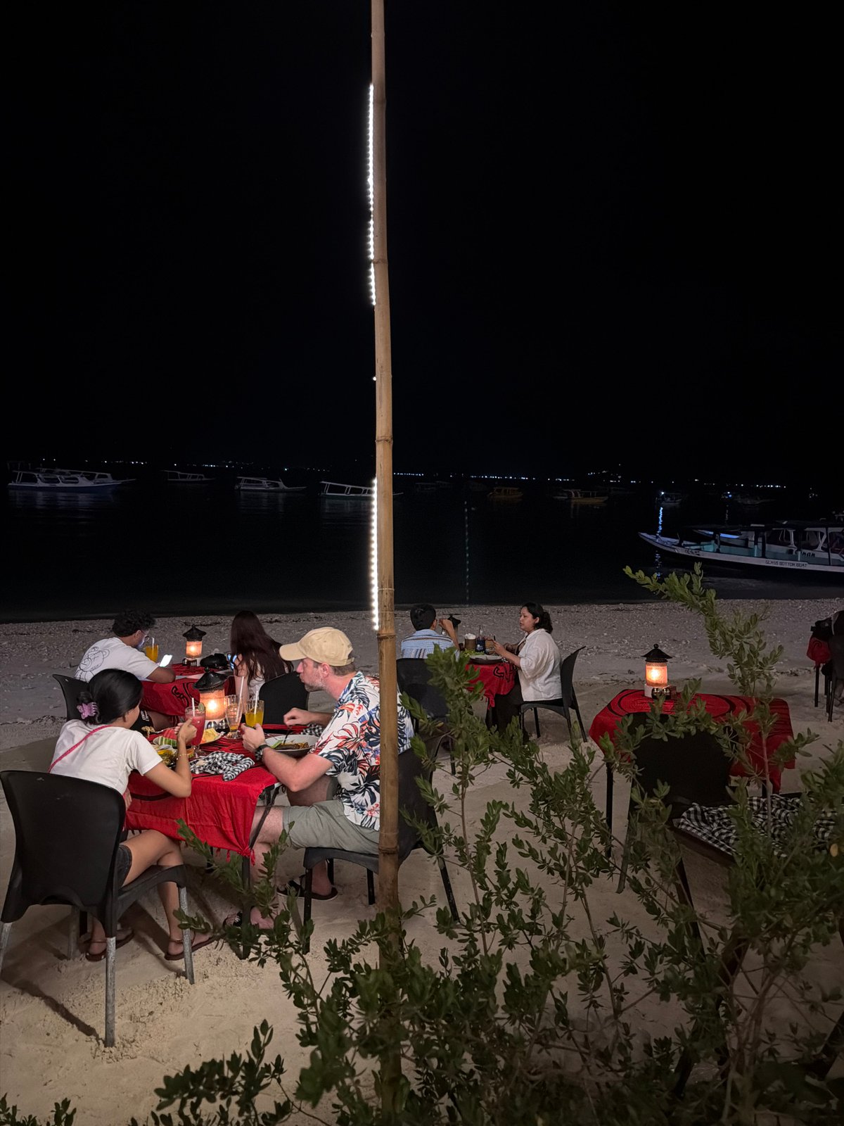 Beachside restaurant serves diners under lanterns in Indonesia